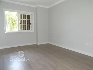 Ambiente interno de uma sala com piso de madeira clara e janela.