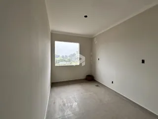 Vista interna de um ambiente com paredes brancas e piso de concreto.