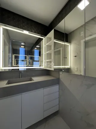 Foto de um banheiro moderno com bancada e espelhos iluminados.