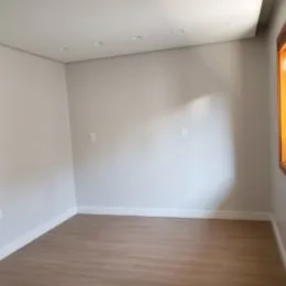 Foto de um cômodo interno com paredes brancas e piso de madeira.