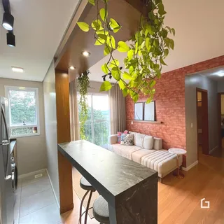 Ambiente interno de uma sala de estar com piso de madeira e parede de tijolos aparentes.