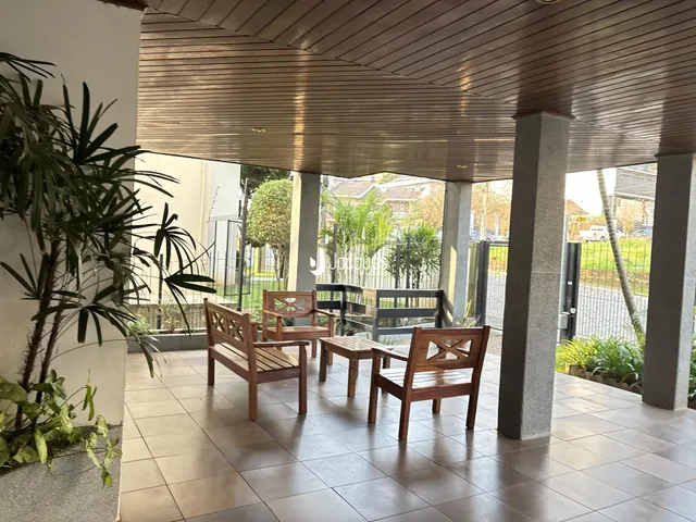 Área externa coberta com móveis de madeira e piso de cerâmica.