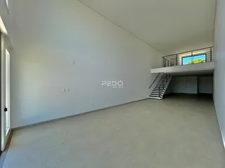 Espaço interno amplo com paredes brancas e piso claro.