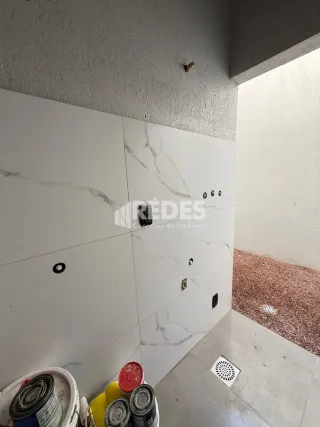Canto de parede interno com revestimento de mármore e piso de concreto.