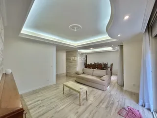Sala de estar moderna com piso de madeira clara e sofá de cor clara.