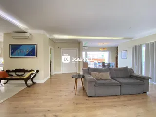 Sala de estar com sofá cinza e piso de madeira clara.