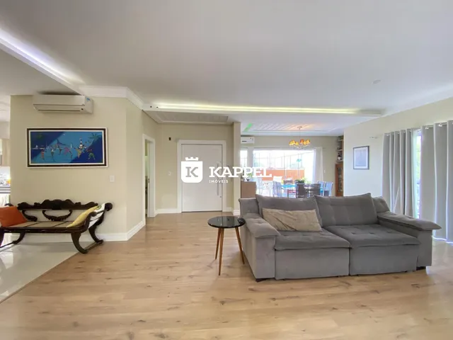 Sala de estar com sofá cinza e piso de madeira clara.