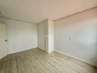 Interior de uma sala de estar com piso de madeira clara e paredes brancas.