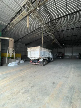 Espaço interno industrial com estrutura de telhado metálico e piso de concreto.