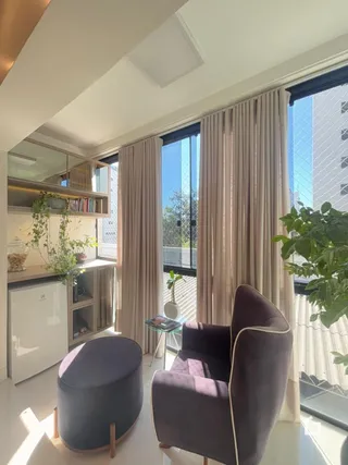 Sala de estar com grandes janelas e cortinas claras.