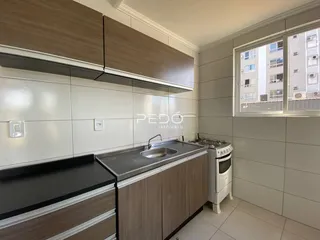 Cozinha com armários de madeira e revestimento branco.
