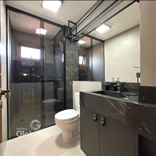 Banheiro moderno com box de vidro e revestimento em mármore escuro.