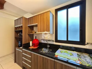 Cozinha com armários de madeira e bancada escura.