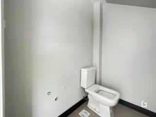 Vista de um corredor com um vaso sanitário branco em uma residência.