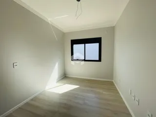 Foto de um cômodo interno com paredes brancas e piso de madeira clara.