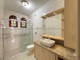 Foto interna de um banheiro com revestimento cerâmico e box de vidro.