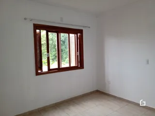 Foto de um cômodo interno com parede branca e janela de madeira.