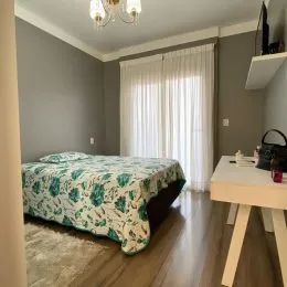 Quarto com cama e cortinas brancas em um ambiente interno.
