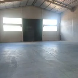 Foto de um espaço interno amplo com piso de concreto e paredes brancas.