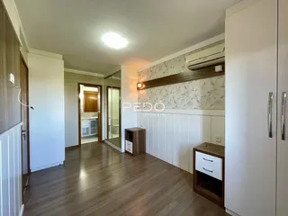 Hall de entrada com piso de madeira e paredes brancas em uma residência.