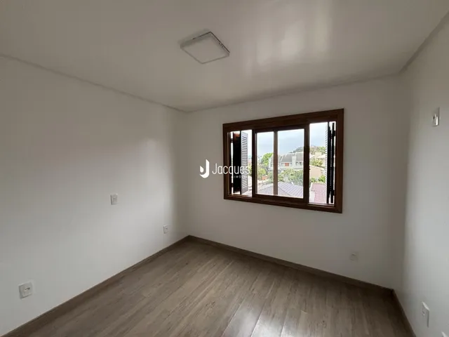 Ambiente interno de uma sala com piso de madeira e janela.