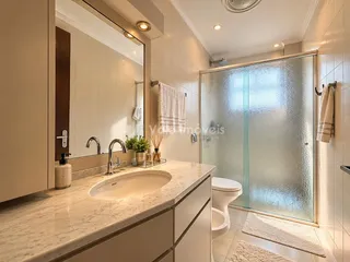 Banheiro moderno com box de vidro e bancada de mármore claro.