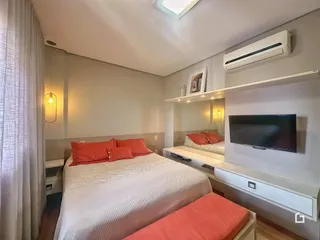Quarto com cama e televisão em ambiente moderno.