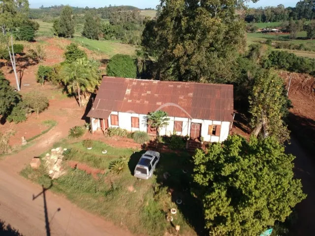 Foto aérea da fachada de uma casa em Lajeado, Brasil, cercada por vegetação e terra.