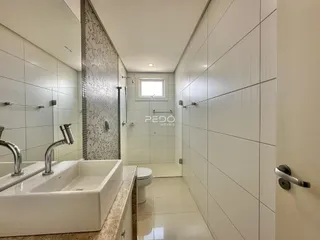 Banheiro com revestimento cerâmico branco e bancada de pia.