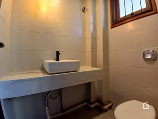 Foto de um banheiro com azulejos brancos e pia de apoio.