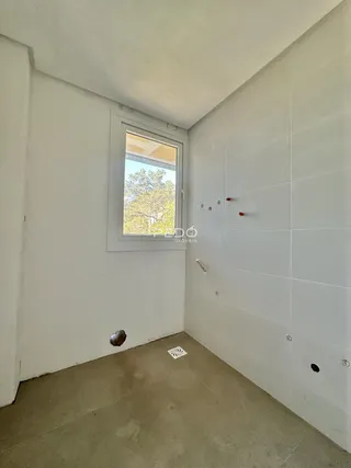 Vista interna de um corredor com paredes brancas e piso de cor terrosa.
