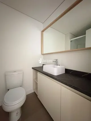 Foto do interior de um banheiro com vaso sanitário e bancada.
