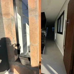 Foto de um corredor interno com paredes brancas e piso claro.