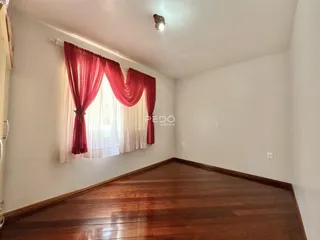 Imagem de uma sala de estar com piso de madeira e cortinas vermelhas.