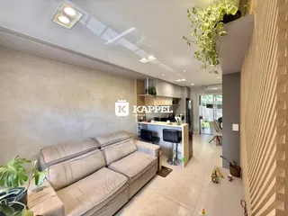 Uma sala de estar moderna com sofá grande e área de cozinha integrada.