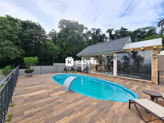 Foto da área externa com piscina e deck de madeira de uma propriedade em Lajeado.