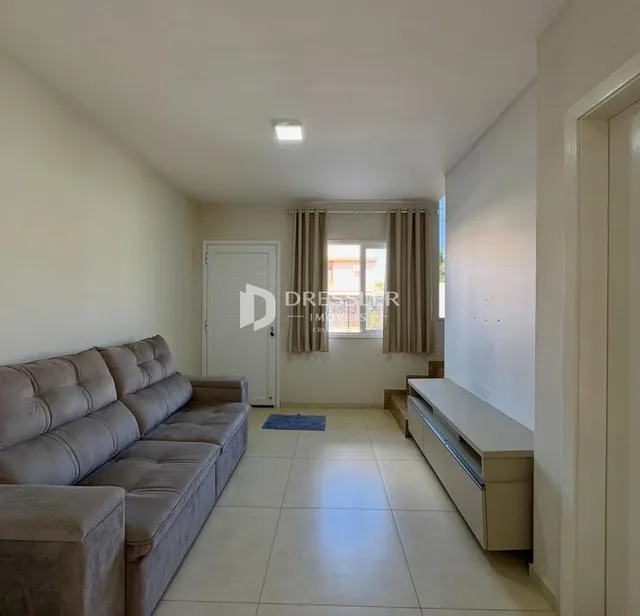 Sala de estar com sofá e piso de cerâmica clara.