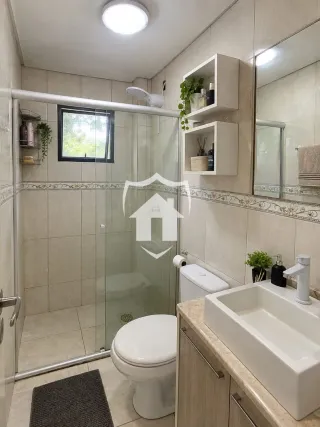 Foto de um banheiro com box de vidro e revestimento cerâmico.