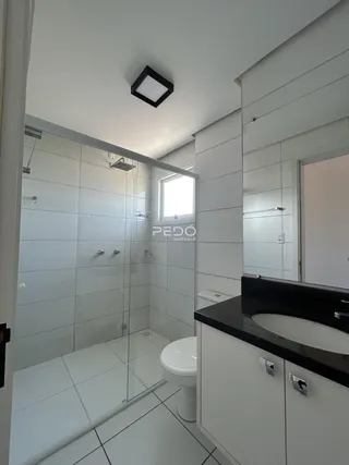 Banheiro com box de vidro e revestimento branco.