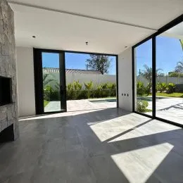 Ambiente interno com piso de concreto e portas de vidro que dão para o exterior.