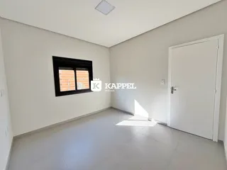 Uma sala de estar ampla com paredes brancas e piso claro.