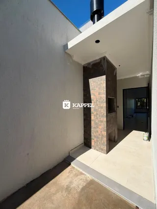 Vista da fachada de uma residência moderna com parede branca e detalhes em tijolo em Lajeado, Brasil.