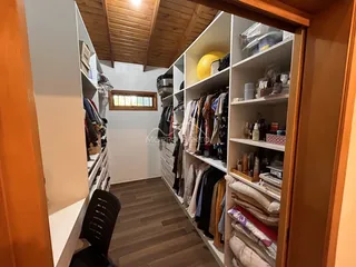 Interior de um corredor com estantes de madeira e roupas penduradas.
