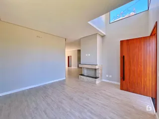 Ambiente interno de uma sala de estar com piso de madeira clara e parede de madeira no ambiente.