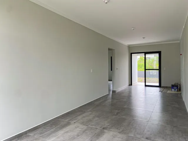 Corredor com paredes brancas e piso de cerâmica cinza.