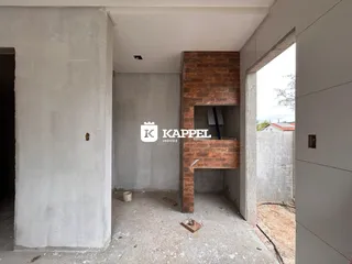 Ambiente interno em construção com paredes de concreto aparente e estrutura de tijolos exposta.