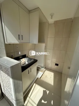 Foto de uma cozinha com armários brancos e bancada escura.