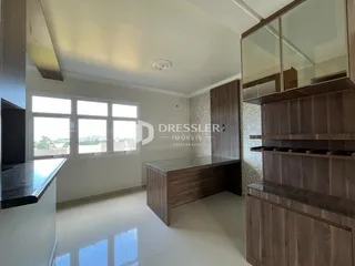 Sala de estar com grandes janelas e armários modernos em um imóvel no Brasil.