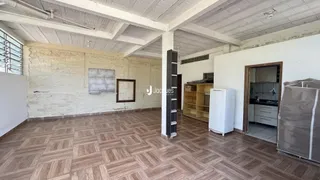 Ambiente interno com paredes de alvenaria e piso de madeira no imóvel.
