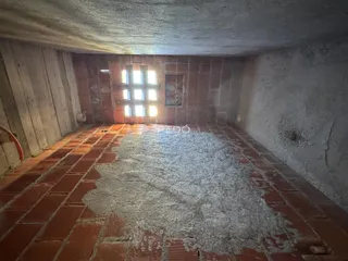 Interior de uma sala com piso de tijolos aparentes e paredes de alvenaria.
